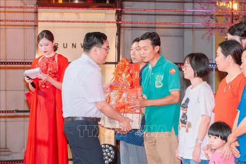 TP.HCM tổ chức chương trình vui Tết cho 1.000 gia đình thanh niên- Ảnh 2. Anh Ngô Minh Hải, Phó Bí thư Thường trực Thành đoàn, Chủ tịch Hội Liên hiệp Thanh niên Việt Nam TP.HCM (áo trắng) trao quà cho các gia đình thanh niên công nhân - Ảnh: TTXVN