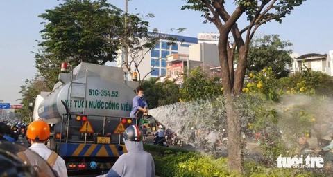 Giờ cao điểm, hàng trăm xe ùn lại trên đường Điện Biên Phủ vì xe tưới nước- Ảnh 4. Trong khi các xe gắn máy cố lách khỏi "vòng vây" này, người đàn ông đứng phía sau xe bồn vẫn ra sức cầm vòi xịt tưới cây