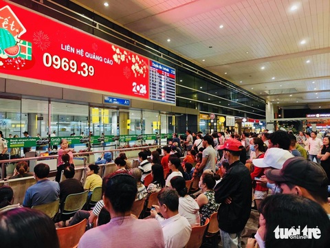 Chộn rộn đón Việt kiều về quê lúc nửa đêm, Tân Sơn Nhất đông đúc người- Ảnh 2. Đông đảo người dân ngồi chờ sẵn ngay trước cửa ra để có thể gặp mặt người thân nhanh nhất - Ảnh: ĐỨC THIỆN