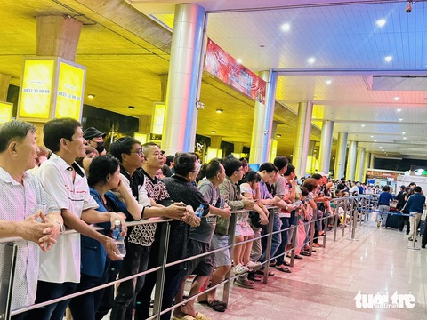 Chộn rộn đón Việt kiều về quê lúc nửa đêm, Tân Sơn Nhất đông đúc người- Ảnh 4. Bên ngoài, nhiều người tựa vào lan can để trông ngóng người thân từ phương xa trở về - Ảnh: CÔNG TRUNG