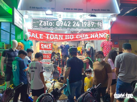 Quần áo, giày dép xả hàng nhiều nơi, chen chân tới nửa đêm ‘săn’ hàng ở TP.HCM- Ảnh 1. Một cửa hàng quần áo trên đường Nguyễn Trãi (quận 5) xả kho toàn bộ cửa hàng, khách mua vây kín sạp - Ảnh: NHẬT XUÂN