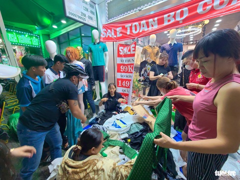 Quần áo, giày dép xả hàng nhiều nơi, chen chân tới nửa đêm ‘săn’ hàng ở TP.HCM- Ảnh 2. Áo sơ mi, áo thun, quần jeans được đổ đống ra vỉa hè, giá chỉ từ 99.000 - 149.000 đồng - Ảnh: NHẬT XUÂN
