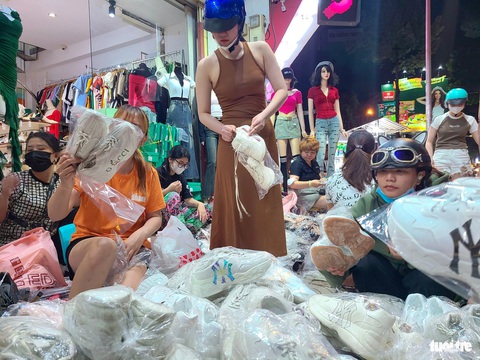 Quần áo, giày dép xả hàng nhiều nơi, chen chân tới nửa đêm ‘săn’ hàng ở TP.HCM- Ảnh 5. Giày dép xả kho đồng giá 100.000 đồng hút khách - Ảnh: NHẬT XUÂN