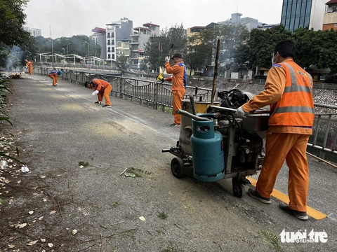 Lần đầu tiên Hà Nội có tuyến đường dành riêng cho xe đạp- Ảnh 1. Công nhân kẻ lại vạch sơn đường, dọn dẹp tuyến đường dọc sông Tô Lịch để dành riêng cho xe đạp - Ảnh: QUANG VIỄN