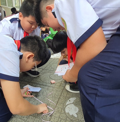 Được giao tính diện tích bàn ăn, học sinh lớp 5 than Tranh luận và đo đi đo lại để tìm chu vi viên gạch trên sân trường - Ảnh: HOÀNG HƯƠNG