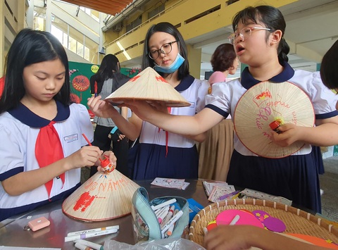 Được giao tính diện tích bàn ăn, học sinh lớp 5 than Sau khi vượt qua các trạm thử thách, học sinh dừng chân ở trạm cuối cùng "Xuân với hình tròn" để trang trí nón lá, lắp ráp... - Ảnh: HOÀNG HƯƠNG