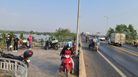 Chạy xe về Tết, người dân có nên dừng xe trên những cây cầu để chụp hình?- Ảnh 1. Tại điểm kết nối giữa cầu Rạch Miễu xuống Cồn Phụng (tỉnh Bến Tre), nhiều người đi xe máy dừng lại chụp hình và khi nhập làn trở lại cầu Rạch Miễu thì sẽ rất nguy hiểm. Trong ảnh: Một nhóm bạn trẻ đang dừng lại để chụp hình sáng 27-1 - Ảnh: MẬU TRƯỜNG