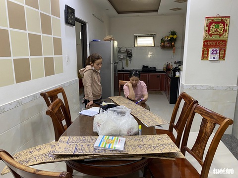 Làng ‘nấu tiệc’ cuối năm, những tờ đơn đặt hàng dài cả mét- Ảnh 2. Vợ ông Thông phải ngồi trực điện thoại ghi đơn đặt của khách dài từng xấp - Ảnh: B.D.