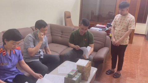 Bộ Công an bắt 'tú ông' điều hành mại dâm có người mẫu, diễn viên, ca sĩ- Ảnh 1. Lực lượng chức năng làm việc với Nguyễn Hữu Thái (đứng) - Ảnh: Công an cung cấp