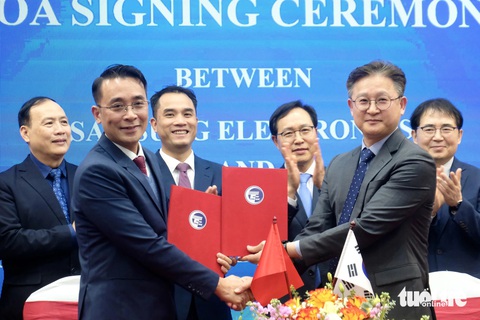 Trường đại học Công nghệ 'bắt tay' Samsung đào tạo nhân lực bán dẫn và vi mạch- Ảnh 1. GS.TS Chử Đức Trình, hiệu trưởng Trường đại học Công nghệ (thứ hai từ trái) và ông Chang Yong Kim - phó tổng giám đốc Samsung Electronics - thực hiện ký thỏa thuận - Ảnh: NGUYÊN BẢO