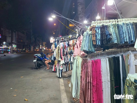 Cửa hàng thời trang 'lay lắt' đợi khách tới khuya- Ảnh 5. Nhiều chủ cửa hàng bấm điện thoại giết thời gian buổi đêm - Ảnh: NHẬT XUÂN