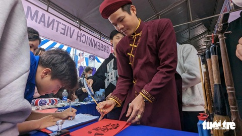 Tư vấn tuyển sinh tại Huế: Học sinh hào hứng tìm hiểu ngành nghề- Ảnh 2. Ông đồ cho chữ tại gian tư vấn của Trường đại học Greenwich - Ảnh: NHẬT LINH