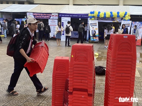 Cô trò cùng nhau xếp ghế, nhặt rác sau chương trình tư vấn tuyển sinh- Ảnh 2. Một bạn nam tự động xếp ghế nhựa lại thành từng chồng để hỗ trợ các cô chú lao công tại chương trình - Ảnh: TẤN VŨ