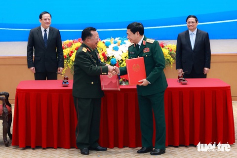 Thúc đẩy làm đường cao tốc, đường sắt nối Việt Nam và Lào- Ảnh 4. Hai Thủ tướng chứng kiến lễ ký kết và trao văn kiện hợp tác giữa hai Bộ Quốc phòng - Ảnh: NGUYỄN KHÁNH
