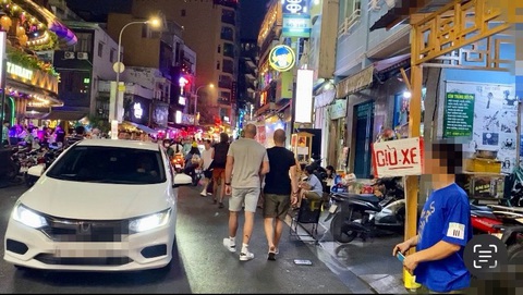 Cận cảnh những bãi giữ xe ‘chặt chém’ dịp cuối năm- Ảnh 3. Một người đàn ông (áo xanh) chèo kéo khách vào gửi xe tại hẻm 183 Bùi Viện (phường Phạm Ngũ Lão, quận 1) giá 50.000 đồng/đêm, với điều kiện cứ nhân tiền theo số ngày thì thích gửi bao lâu cũng được - Ảnh: TIẾN QUỐC