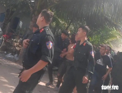 Đã bắt được nghi phạm giết người ở Hóc Môn lẩn trốn tại Long An- Ảnh 1. Nghi phạm (cởi trần, bịt mặt) được lực lượng chức năng dẫn giải ra khỏi khu vực khoanh vùng - Ảnh: NGỌC KHẢI