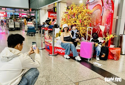 Sân bay Tân Sơn Nhất đông khách hơn nhưng vẫn ổn- Ảnh 7. Khách tới sân bay sớm, tạo dáng chụp hình check-in chuyến bay ngày Tết - Ảnh: CÔNG TRUNG
