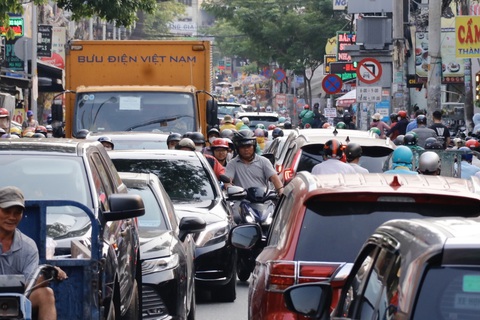 Khu vực Tân Sơn Nhất ken đặc xe những ngày giáp Tết- Ảnh 8. Xe máy luồn lách qua khe hở giữa hàng xe ô tô trên đường Phạm Văn Bạch (quận Tân Bình) - Ảnh: TIẾN QUỐC