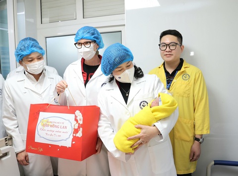 Bộ trưởng Bộ Y tế Đào Hồng Lan thăm và động viên y bác sĩ đêm giao thừa- Ảnh 1. Bộ trưởng Đào Hồng Lan bế một trong những em bé chào đời trong đêm giao thừa, kế bên bà Lan là trưởng đại diện Tổ chức Y tế thế giới - Ảnh: TRẦN MINH