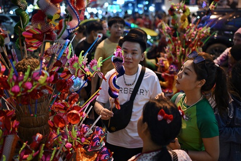 Người bán hàng rong trên đường phố Bangkok bày bán những món đồ chơi hình rồng trong đêm 30, rạng sáng mùng 1 Tết - Ảnh: AFP Người bán hàng rong trên đường phố Bangkok bày bán những món đồ chơi hình rồng trong đêm 30, rạng sáng mùng 1 Tết - Ảnh: AFP