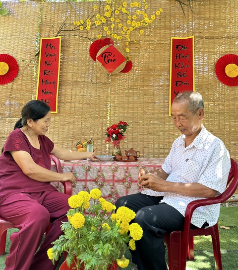 Cậu học trò lớp 11 làm Ông bà chụp hình kỷ niệm bên tiểu cảnh Tết do cháu làm.