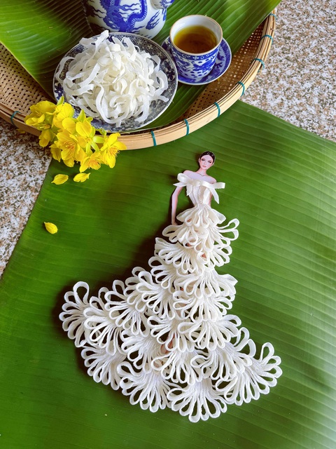 Bộ sưu tập làm từ mứt Tết ‘có một không hai’ của Nguyễn Minh Công- Ảnh 2. Với thiết kế từ mứt dừa, Nguyễn Minh Công đã cùng gia đình làm loại mứt dừa hoa kỳ công của ông bà thời xưa để mang vào mẫu thiết kế này. Từng thực hiện thiết kế làm từ mứt dừa, Nguyễn Minh Công ở bộ sưu tập mứt Tết lại thổi hồn vào thiết kế này nét khác biệt bằng việc tận dụng những cánh hoa của mứt dừa để làm họa tiết ren cho thiết kế. Một chiếc váy cưới đã được tạo nên dưới bàn tay của Nguyễn Minh Công nhờ những họa tiết ren từ mứt dừa và điểm nhấn bởi phần nơ trên vai áo.