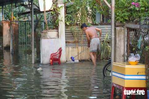 Tiền Giang: Nhiều tuyến đường, nhà cửa bị ngập do triều cường- Ảnh 4. Người dân tìm cách lấy rác, khơi thông dòng nước tại cống nhằm giúp nước chảy nhanh hơn - Ảnh: HOÀI THƯƠNG