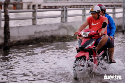 Triều cường đạt đỉnh, người dân TP.HCM bì bõm dắt xe ngày mùng 3 Tết- Ảnh 4. Càng về tối nước triều càng dâng cao, đường Trần Xuân Soạn đã ngập lên xấp xỉ đầu gối