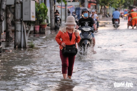 Triều cường đạt đỉnh, người dân TP.HCM bì bõm dắt xe ngày mùng 3 Tết- Ảnh 8. Một người dân lội nước đi về nhà