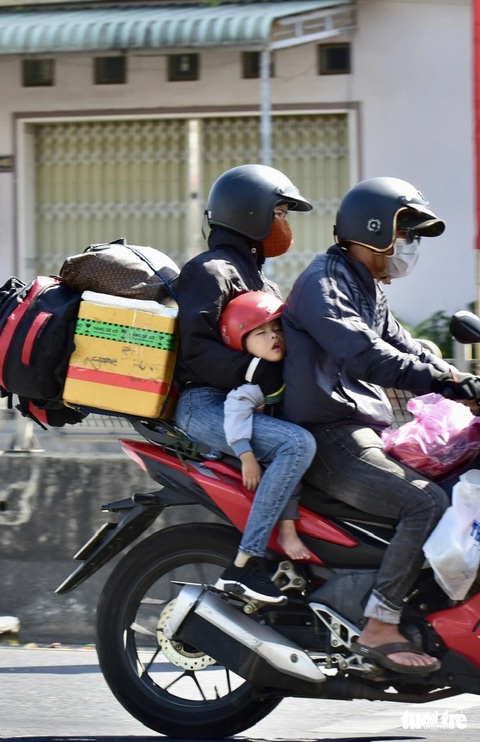 Người đi xe máy thoải mái trở về TP.HCM trên quốc lộ thông thoáng- Ảnh 9. Đứa bé ngủ say trên xe - Ảnh: T.T.D
