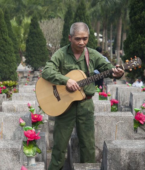 Bảo vệ từng tấc đất biên giới phía Bắc, có những người lính mãi đôi mươi- Ảnh 1. Cựu chiến binh, nhạc sĩ Trương Quý Hải hát bên những ngôi mộ của đồng đội năm xưa đã ngã xuống ở nghĩa trang quốc gia Vị Xuyên, Hà Giang