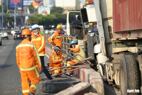 Container tông dải phân cách cầu Sài Gòn, Thủ Đức vào trung tâm TP kẹt cứng 3km- Ảnh 7. Công nhân cầu đường đang dọn dẹp hiện trường, một bánh xe container bị văng ra - Ảnh: MINH HÒA