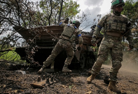 Tướng Nga: Binh sĩ NATO đang cải trang để chiến đấu ở Ukraine- Ảnh 1. Binh sĩ Ukraine bên xác một xe chiến đấu của Nga - Ảnh: REUTERS