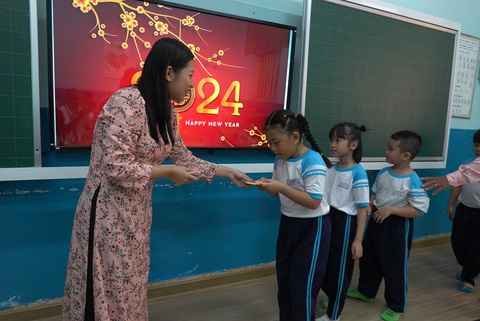 Gần 1,7 triệu học sinh TP.HCM trở lại trường sau kỳ nghỉ Tết dài- Ảnh 2. Giáo viên Trường tiểu học Trần Hưng Đạo, quận 1, lì xì cho học sinh và chúc Tết các em - Ảnh: NHƯ HÙNG