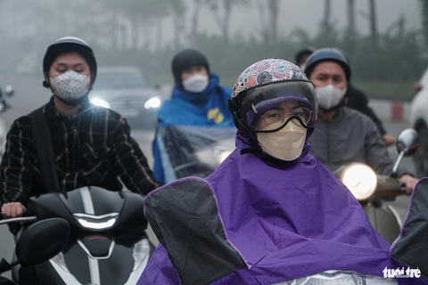 Chùm ảnh sương mù dày đặc, ở Hà Nội mà ngỡ Sa Pa, Đà Lạt- Ảnh 2. Nhiều người Hà Nội phải mặc thêm áo mưa dù trời không mưa, do quá nhiều sương mù - Ảnh: PHẠM TUẤN