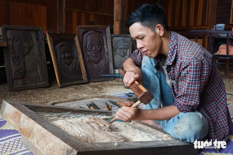 Chàng trai biến cối, chày, trụ trồng tiêu, máng heo… thành tranh khắc gỗ- Ảnh 1. Anh Tăng Minh Thuận biến những khúc gỗ bỏ đi thành tranh khắc gỗ có giá trị - Ảnh: TRẦN HƯỚNG