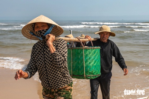 Ngư dân bãi ngang Quảng Trị được mùa ruốc- Ảnh 1. Ngư dân bãi ngang được mùa ruốc, vợ chồng cười hớn hở vì có nguồn thu đáng kể - Ảnh: HOÀNG TÁO