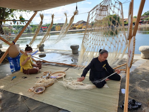 Nghề đan võng và nghề dựng nhà tre, dừa được đưa vào danh mục di sản- Ảnh 1. Nghệ nhân lớn tuổi ở Hội An trình diễn nghề đan võng từ cây ngô đồng tại phố đi bộ - Ảnh: Q.T.