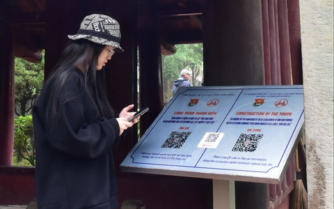 Đi chùa, lễ hội đừng nặng cầu xin- Ảnh 3. Bạn trẻ quét mã QR để tìm hiểu về đền thờ vua Đinh tại cố đô Hoa Lư (Ninh Bình) - Ảnh: T.T.D.