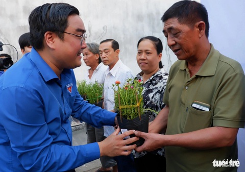 TP.HCM khởi động Tháng thanh niên 2024 tình nguyện vì cộng đồng- Ảnh 1. Phó bí thư thường trực Thành Đoàn TP.HCM Ngô Minh Hải trao hoa và cờ Tổ quốc cho bà con ở chung cư Bình Phú (quận 6) tại lễ ra quân Tháng thanh niên 2024