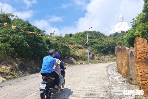 Một du khách ngồi sau xe ôm trong tư thế rất chênh vênh, đầu không đội mũ bảo hiểm - Ảnh: LÂM THIÊN Một du khách ngồi sau xe ôm trong tư thế rất chênh vênh, đầu không đội mũ bảo hiểm