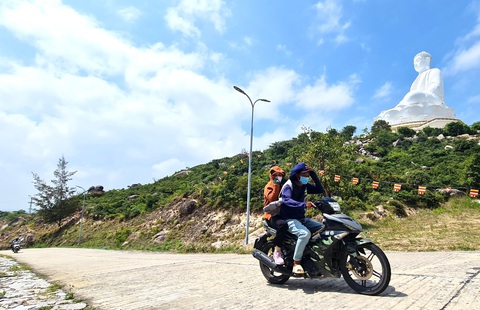 Một xe ôm tự phát chở du khách lên khu vực tượng phật tại chùa ông Núi không đội mũ bảo hiểm, chạy tốc độ cao và lái một tay rất nguy hiểm - Ảnh: LÂM THIÊN Một xe ôm chở du khách lên khu vực tượng Phật tại chùa Ông Núi không đội mũ bảo hiểm, chạy tốc độ cao rất nguy hiểm - Ảnh: LÂM THIÊN