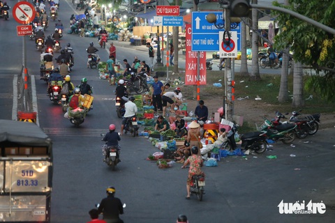 Bày bán rau, củ, quả... dưới lòng đường, đi ngược chiều trước chợ đầu mối Thủ Đức- Ảnh 1. Nhiều người dân lấn chiếm lòng đường quốc lộ 1, bày bán rau củ quả... tiềm ẩn nguy cơ tai nạn