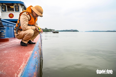 Cảnh sát giao thông đo nồng độ cồn người lái tàu trên tuyến sông Hồng- Ảnh 4. Cảnh sát kiểm tra vạch dấu mớn nước của tàu chở hàng trên sông Hồng - Ảnh: HỒNG QUANG