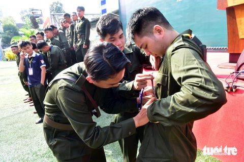 Trại viên Đinh Quốc Trung (giữa) chỉnh cảnh phục cho đồng đội mới. Trong ảnh các trại viên/ thanh niên trúng tuyển nghĩa vụ công an của 10 phường trong quận 1 chuẩn bị chụp ành lưu niệm toàn đội Trại viên Đinh Quốc Trung (giữa) chỉnh cảnh phục cho đồng đội mới, khi các trại viên/thanh niên trúng tuyển nghĩa vụ công an của 10 phường trong quận 1 chuẩn bị chụp ảnh lưu niệm toàn đội
