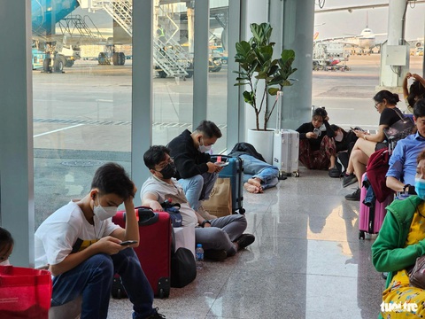 Ra sân bay Tân Sơn Nhất từ nửa đêm, tới sáng vẫn còn vật vờ chưa biết khi nào bay- Ảnh 2. Khách “lớp đứng, lớp ngồi”, nằm ngủ la liệt ở khu chờ ra cửa máy bay - Ảnh: THU DUNG