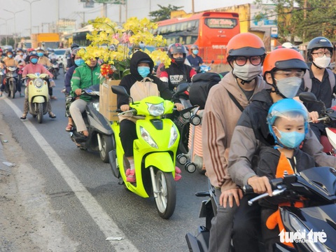 Cửa ngõ phía tây TP.HCM ùn ùn dòng người đổ về quê ăn Tết- Ảnh 2. Nhiều xe máy lỉnh kỉnh đồ đạc, có xe máy còn chở theo chậu hoa - Ảnh: NGỌC KHẢI