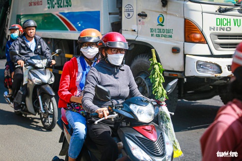 Quốc lộ 50 kẹt cứng từ sáng tới trưa, người về Cần Giuộc, Gò Công đứng chôn chân- Ảnh 7. Người dân lỉnh kỉnh đồ đạc và mang theo hoa, tiền vàng... đi tảo mộ dịp cuối năm