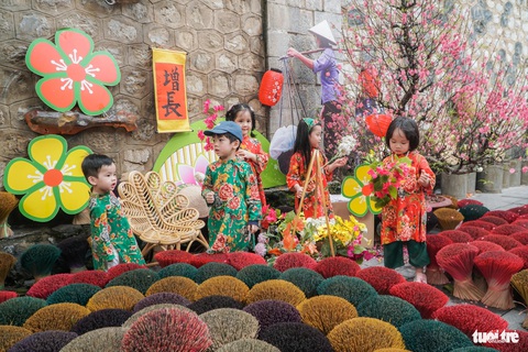 Người Hà Nội đi sắm Tết ngày nắng ấm, phố cổ, trung tâm thương mại kín người- Ảnh 6. Các em nhỏ xúng xính áo dài chụp ảnh đón xuân, ghi nhận trên phố Phùng Hưng - Ảnh: PHẠM TUẤN