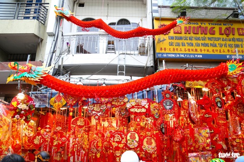 Trưa 25 tháng chạp, người dân TP.HCM xôm tụ sắm Tết- Ảnh 4. Các mô hình rồng lớn, dài hơn 1m được làm từ giấy đỏ thu hút nhiều sự quan tâm của khách hàng. Mỗi mô hình có giá từ 1,2 triệu đồng.